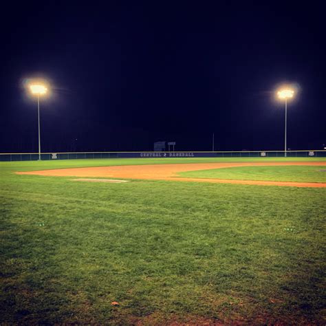 A Group Of People Standing On Top Of A Baseball Field At Night With The